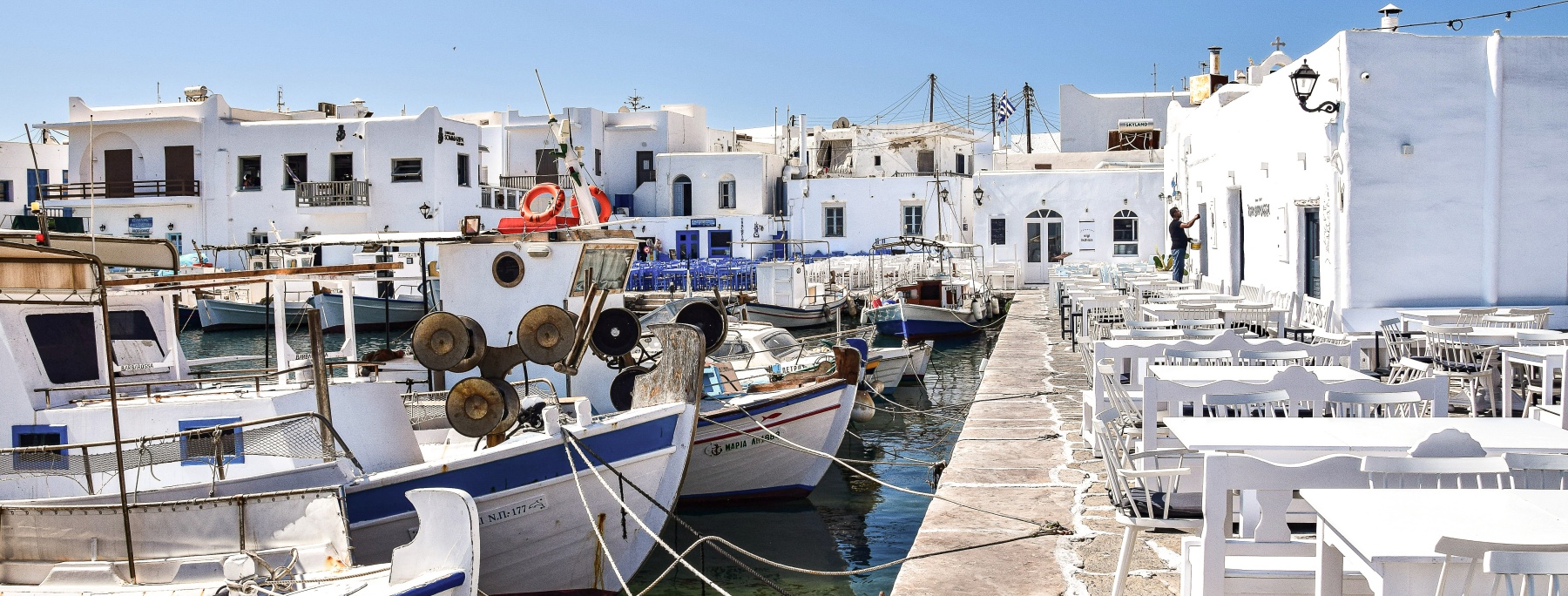 fishing boats in the harbor of paros in front of the promenade