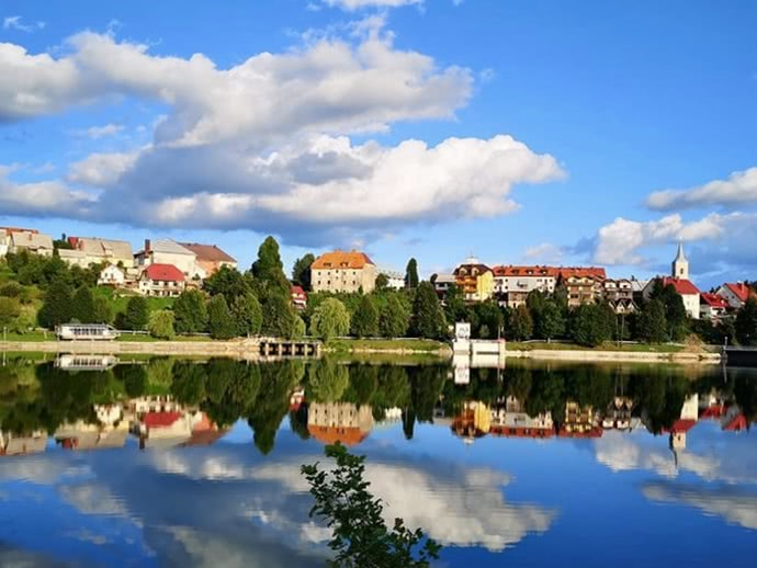Häuser und Kirche spiegeln sich im Fluss