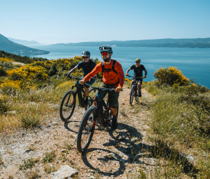 Mountain bikers riding a gravel trail overlooking the sea in North Dalmatia, Croatia.