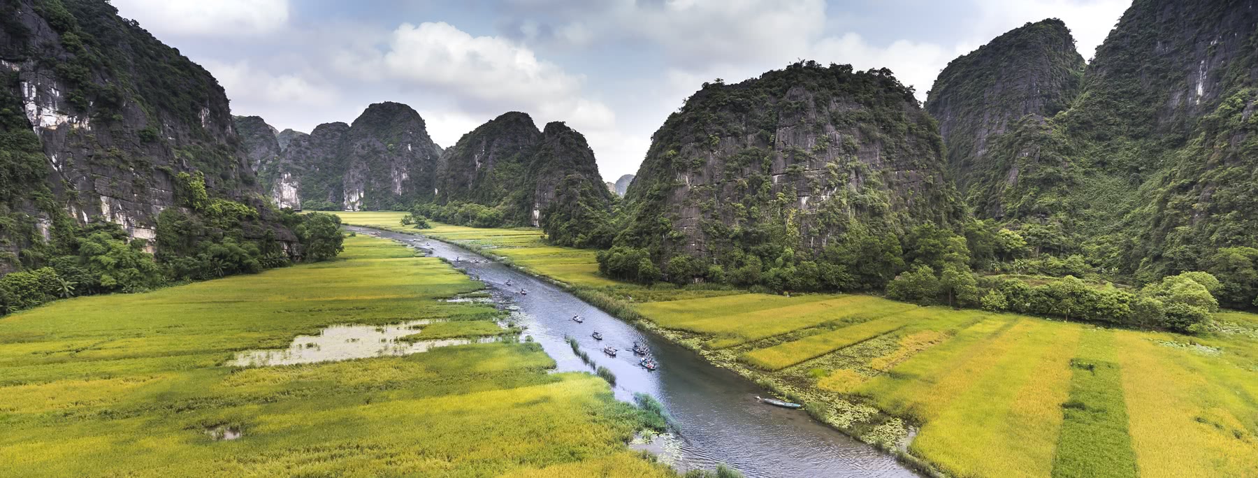 Boote auf dem Fluss in Nin Binh, umgeben von felsigen Ausläufern