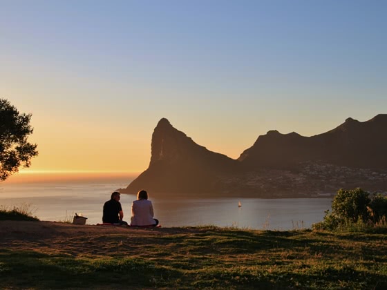Two people looking out over the sea and cliffs at sunset
