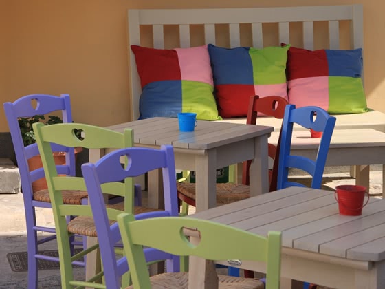 Eating area with wooden tables and colourful chairs and pillows