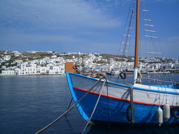 fishing boat in the harbor of mykonos in front of the houses along the promenade