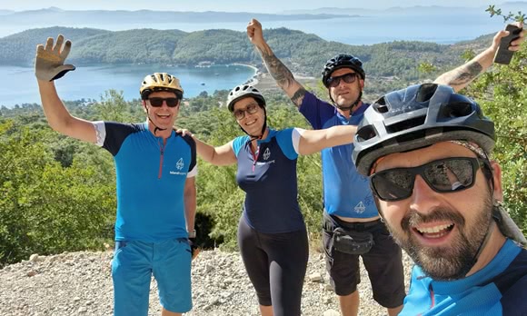 Island hopping tour guides stand on a viewpoint in Turkey and wave at the camera