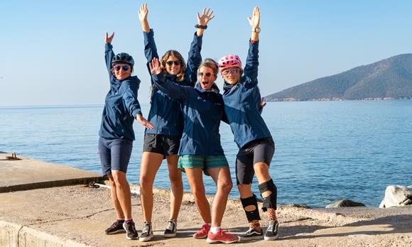 Four female island hopping tour guides pose on a pier by the sea and have fun