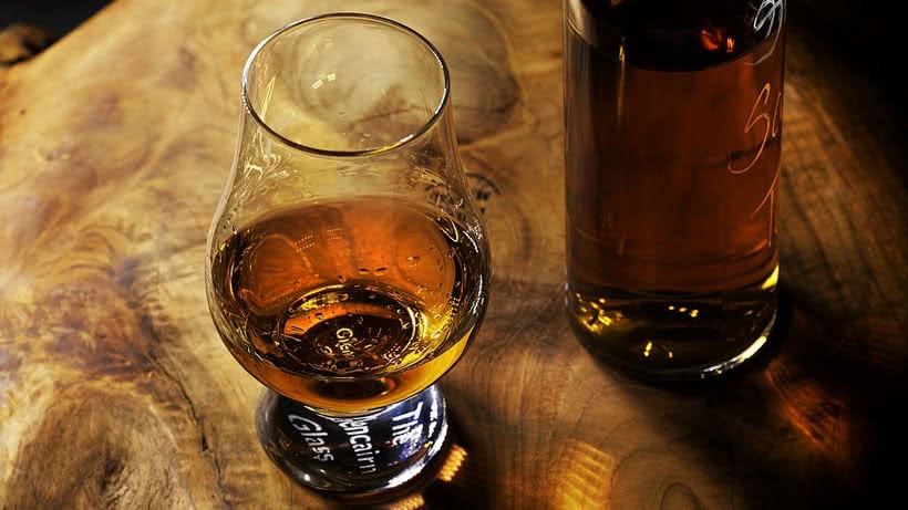 Whiskyglas und Flasche auf Holztisch