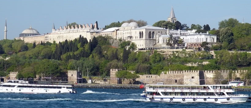 View of Topkapi Palace with river and boats in foreground